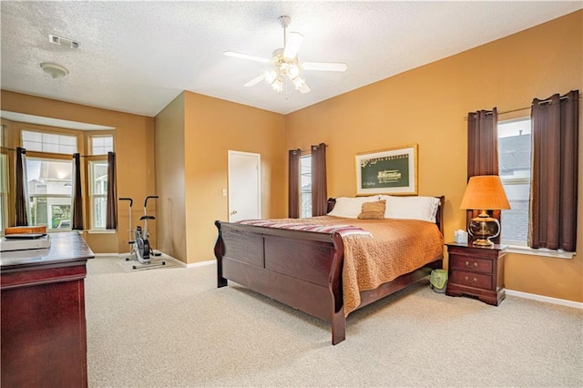 bedroom featuring a textured ceiling, light carpet, and ceiling fan