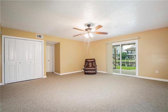 unfurnished room with ceiling fan, carpet flooring, and a textured ceiling