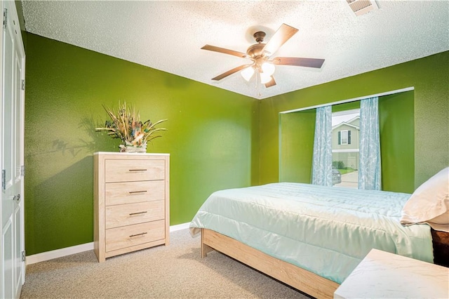 bedroom with ceiling fan, carpet flooring, and a textured ceiling