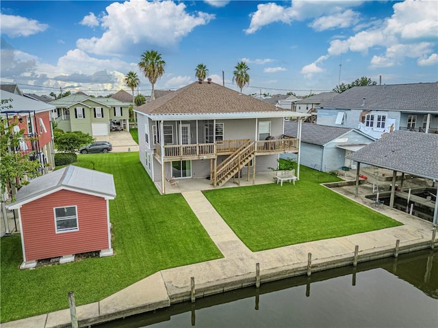 back of property featuring a lawn, a deck with water view, and a patio area