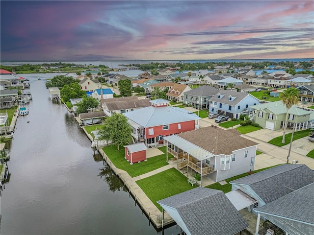 aerial view at dusk featuring a water view