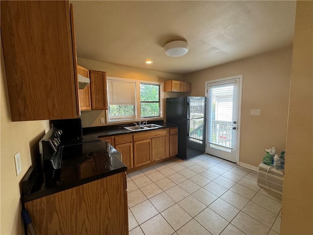 kitchen featuring sink, black fridge, wall chimney exhaust hood, light tile patterned floors, and stove