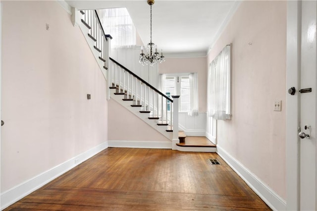 entrance foyer featuring ornamental molding, a notable chandelier, and hardwood / wood-style floors