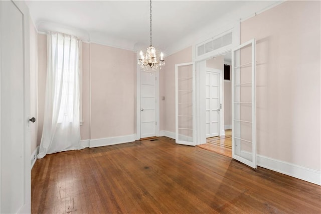 spare room featuring hardwood / wood-style flooring, a wealth of natural light, and a chandelier