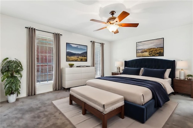 bedroom with ceiling fan, light colored carpet, and multiple windows