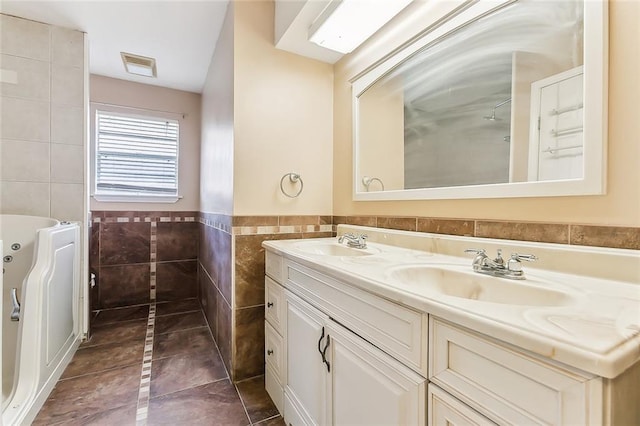 bathroom with a bathing tub, vanity, tile walls, and tile patterned floors