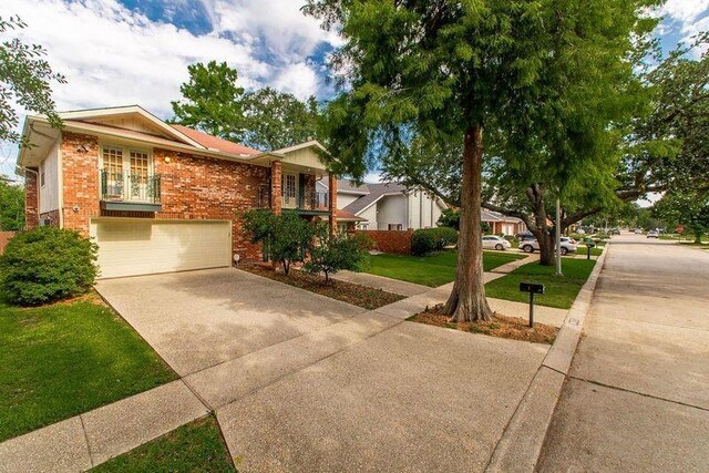 3412 Tolmas Dr, Metairie, LA 70002 - view of front of home with concrete driveway, brick siding, an attached garage, and a front yard