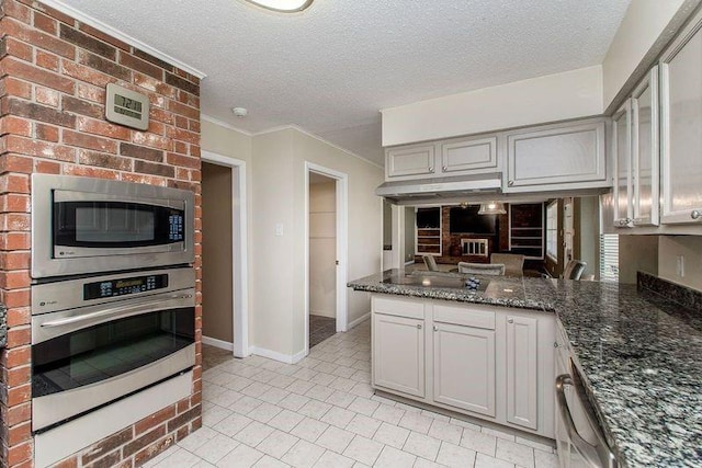 3412 Tolmas Dr, Metairie, LA 70002 - kitchen with appliances with stainless steel finishes, a textured ceiling, gray cabinets, dark stone countertops, and a peninsula