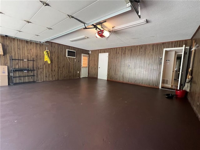 garage featuring a garage door opener and wood walls