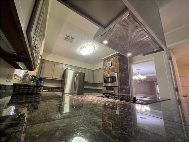 kitchen featuring gray cabinetry, dark stone counters, stainless steel appliances, a textured ceiling, and an inviting chandelier