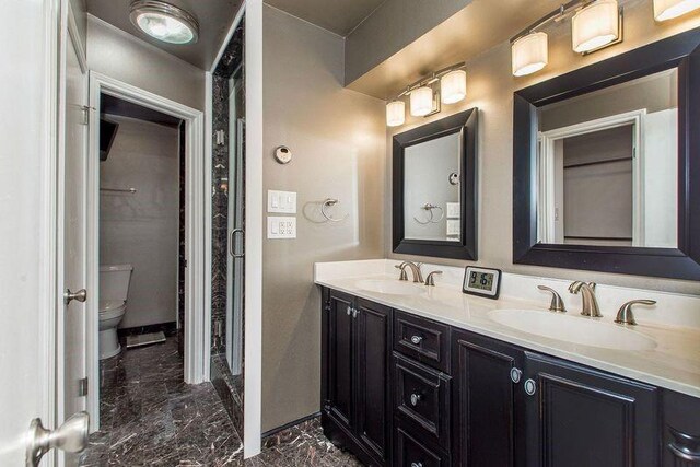 3412 Tolmas Dr, Metairie, LA 70002 - bathroom featuring marble finish flooring, double vanity, toilet, and baseboards