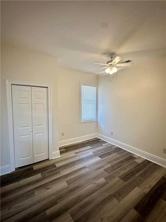 unfurnished bedroom with dark hardwood / wood-style floors, ceiling fan, and a closet