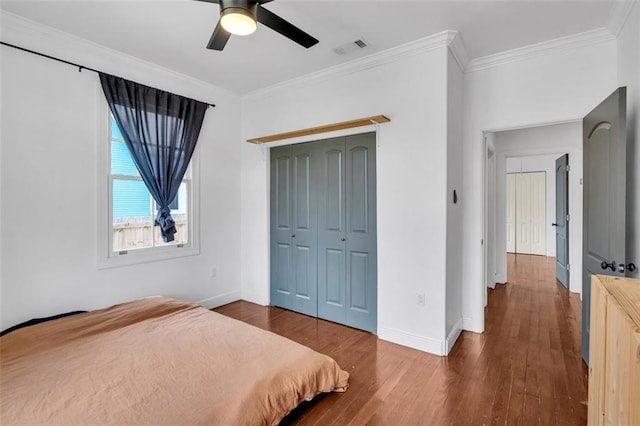 bedroom featuring dark wood-type flooring, ceiling fan, crown molding, and a closet