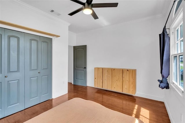 unfurnished bedroom featuring multiple windows, wood-type flooring, and crown molding