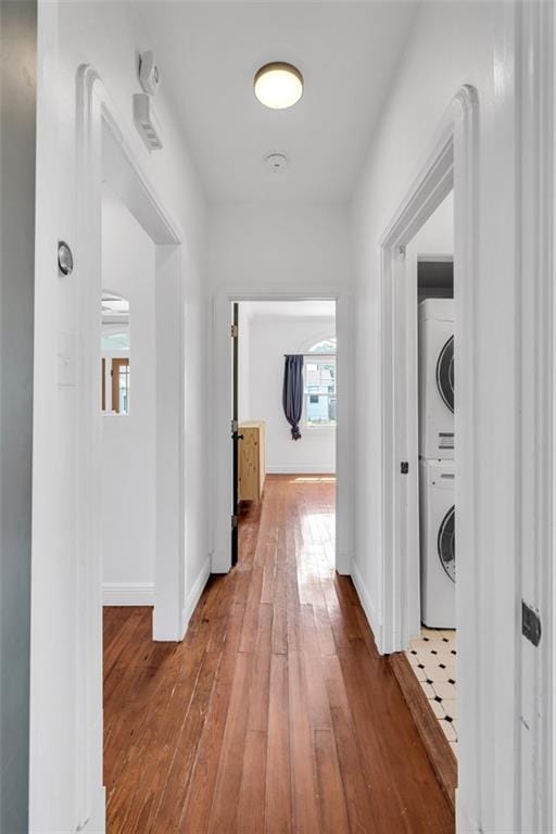 hallway with stacked washer and dryer and wood-type flooring