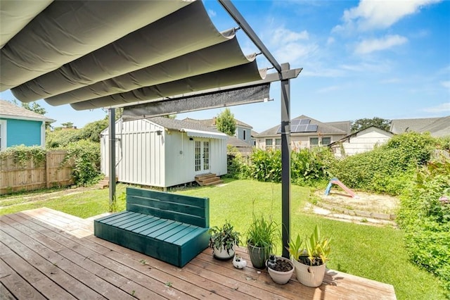 wooden terrace featuring an outdoor structure and a yard