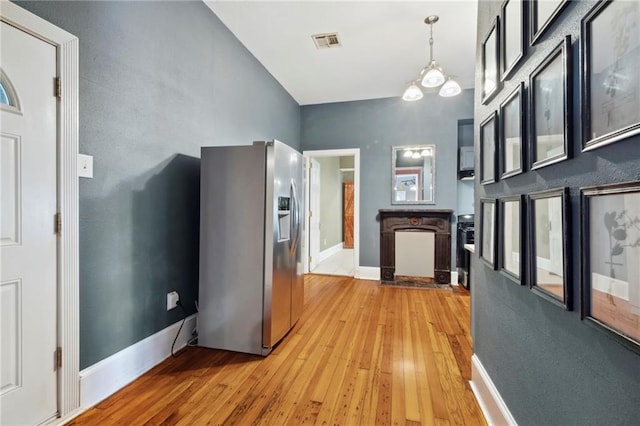 kitchen with pendant lighting, stainless steel fridge, a notable chandelier, and light wood-type flooring