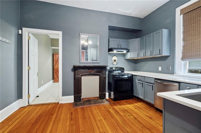 kitchen featuring stainless steel dishwasher, gas stove, light wood-type flooring, and gray cabinetry