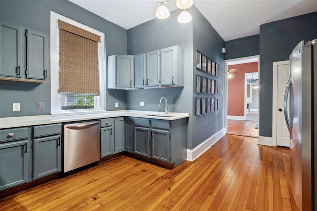 kitchen with stainless steel appliances, gray cabinetry, sink, light hardwood / wood-style floors, and ceiling fan