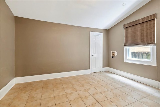 empty room with light tile patterned flooring and vaulted ceiling