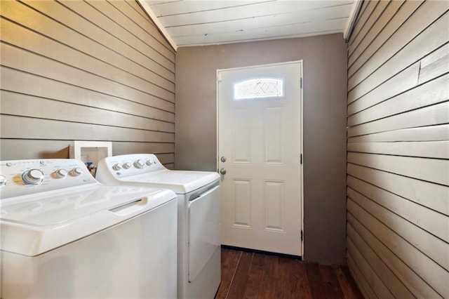 washroom with washing machine and dryer, wooden walls, and dark wood-type flooring