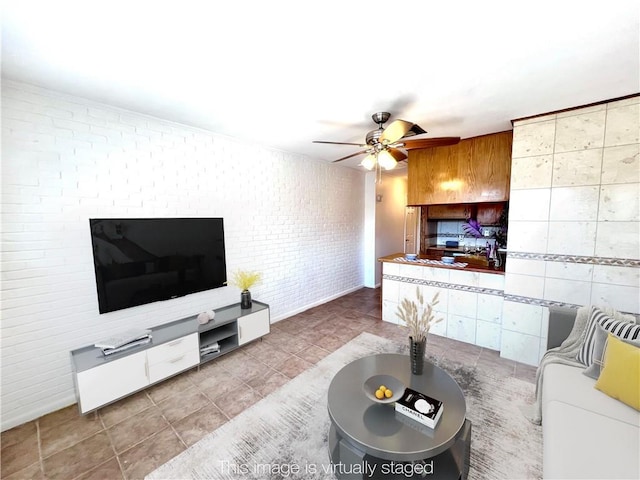 tiled living area featuring a ceiling fan and brick wall