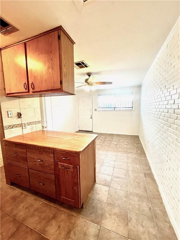 kitchen with brick wall, light tile patterned flooring, and ceiling fan