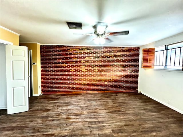 unfurnished room featuring ceiling fan, visible vents, wood finished floors, and brick wall