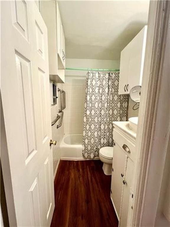 bathroom featuring toilet, wood finished floors, shower / bath combo, and vanity