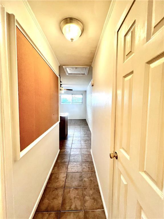 hall featuring baseboards, attic access, and dark tile patterned floors