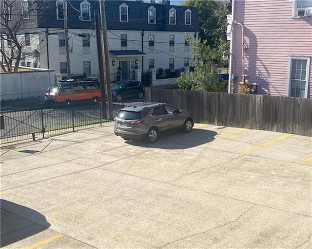 uncovered parking lot featuring fence and cooling unit