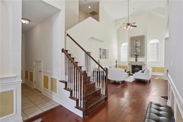 staircase with ceiling fan, hardwood / wood-style floors, and a high ceiling