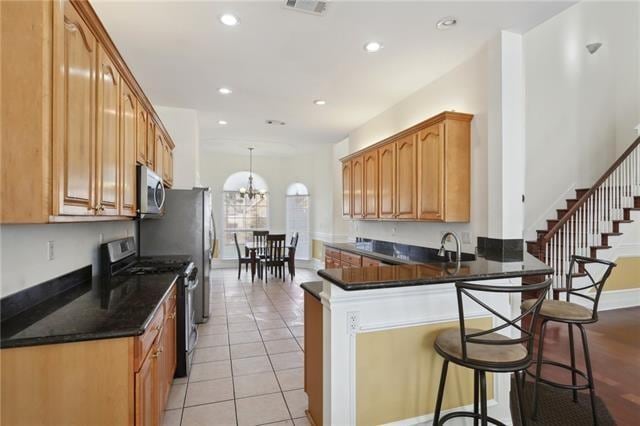 kitchen with kitchen peninsula, pendant lighting, a breakfast bar area, electric range oven, and light tile patterned floors