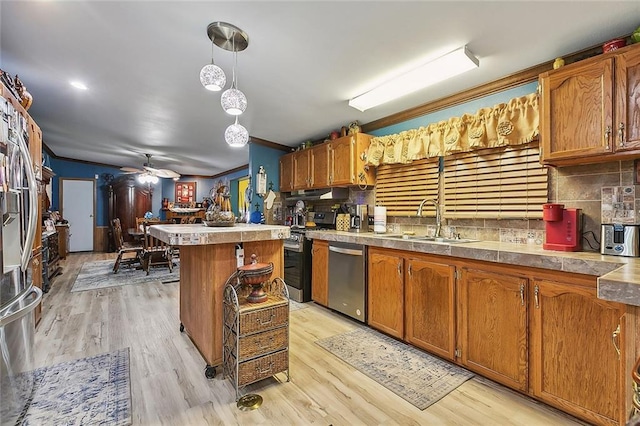 kitchen featuring appliances with stainless steel finishes, pendant lighting, tasteful backsplash, sink, and a center island