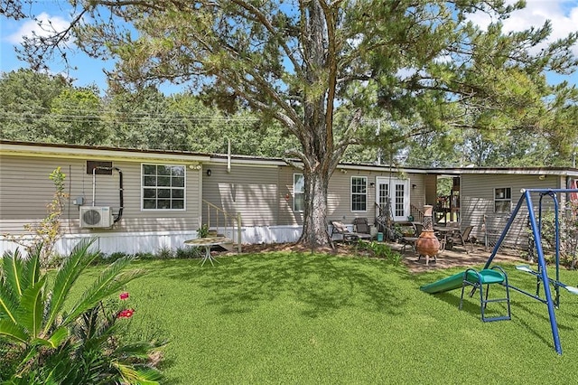 back of house with an outdoor fire pit, a playground, a lawn, and ac unit