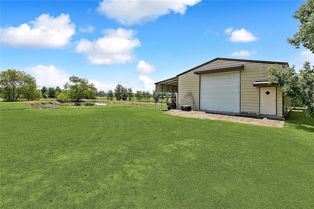 view of yard with a carport, a garage, and an outdoor structure