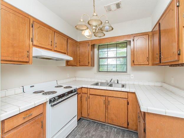 kitchen with decorative light fixtures, white range with electric stovetop, a chandelier, dark hardwood / wood-style flooring, and sink