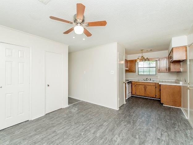 kitchen featuring range, ceiling fan with notable chandelier, sink, dark hardwood / wood-style floors, and a textured ceiling