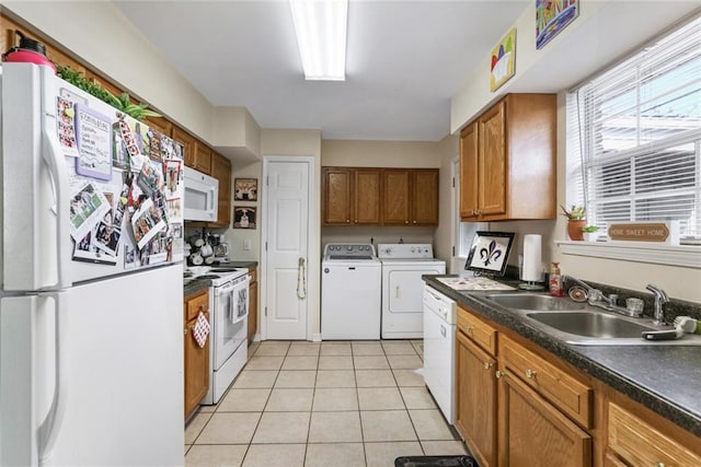 kitchen featuring light tile patterned flooring, white appliances, washer and clothes dryer, and sink