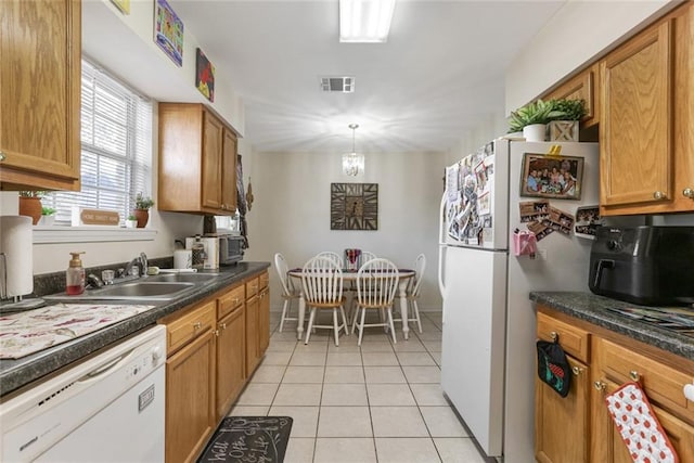 kitchen featuring sink, hanging light fixtures, light tile patterned floors, a notable chandelier, and white appliances