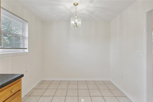 unfurnished dining area with light tile patterned floors and an inviting chandelier