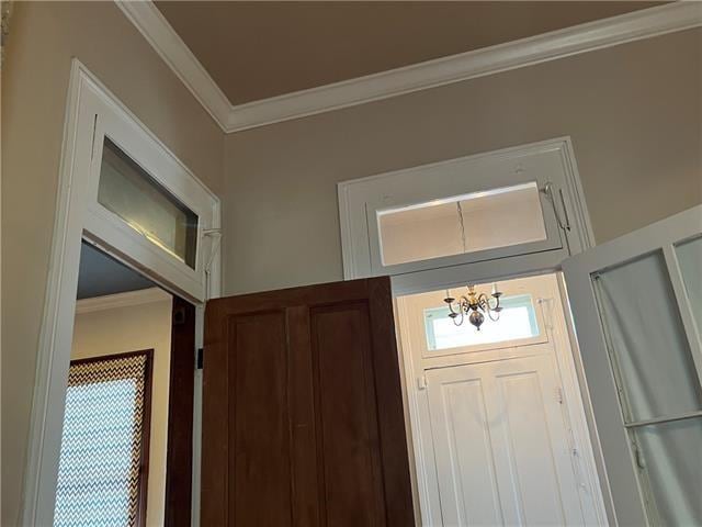 foyer with ornamental molding and a notable chandelier