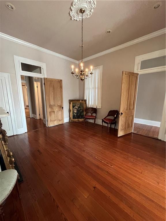 unfurnished dining area featuring a chandelier, crown molding, and dark wood-type flooring