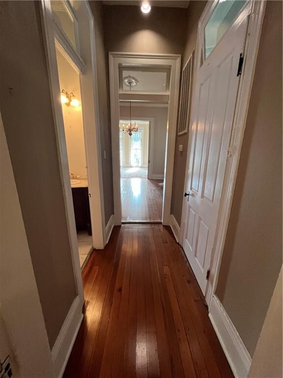 hallway with an inviting chandelier and dark wood-type flooring