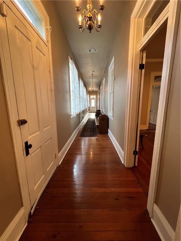 hall featuring dark hardwood / wood-style floors, ornamental molding, and a chandelier