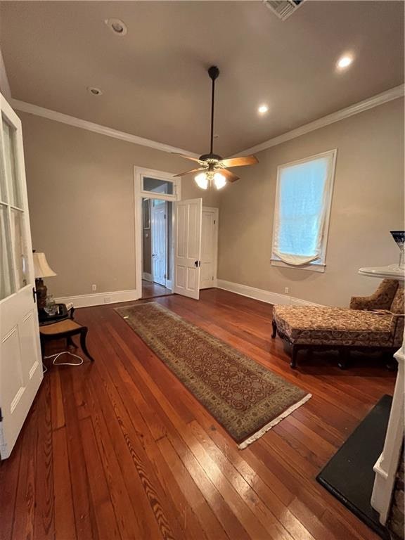 interior space with crown molding, ceiling fan, and dark wood-type flooring