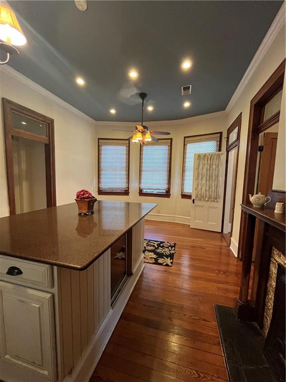 kitchen featuring dark hardwood / wood-style flooring, a center island, ceiling fan, and ornamental molding