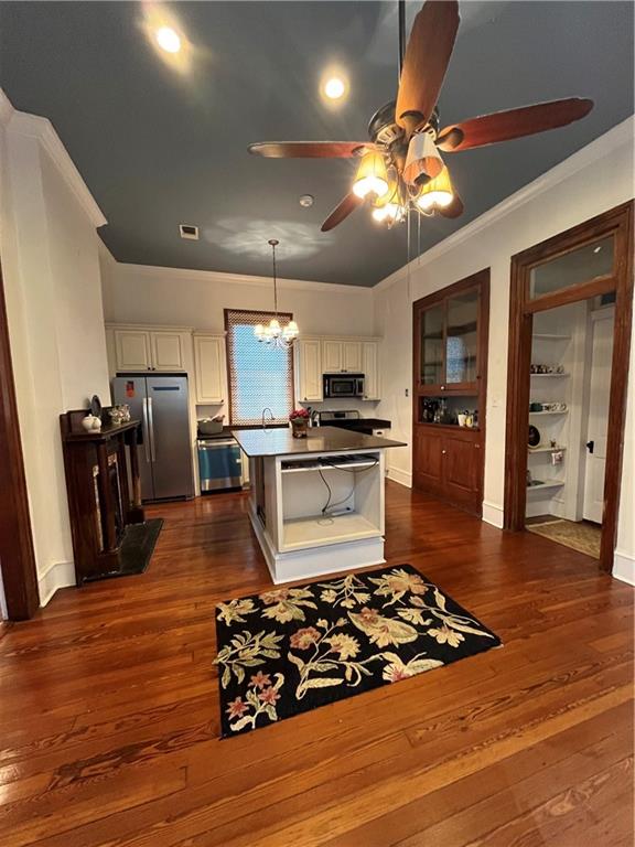 kitchen featuring dark hardwood / wood-style flooring, white cabinets, a kitchen island, and appliances with stainless steel finishes