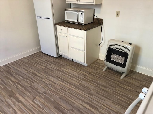 kitchen with dark hardwood / wood-style floors, heating unit, white cabinets, and white appliances