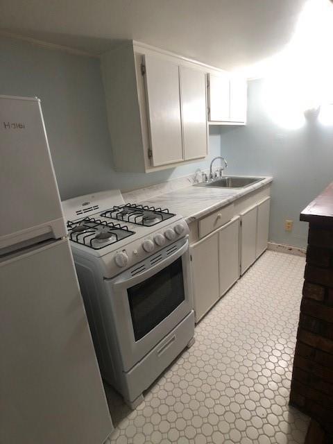 kitchen with sink, white cabinets, and white appliances